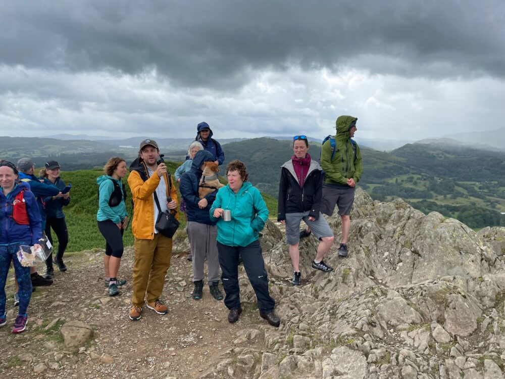 Several people standing on the summit of Loughrigg enjoying the summit party